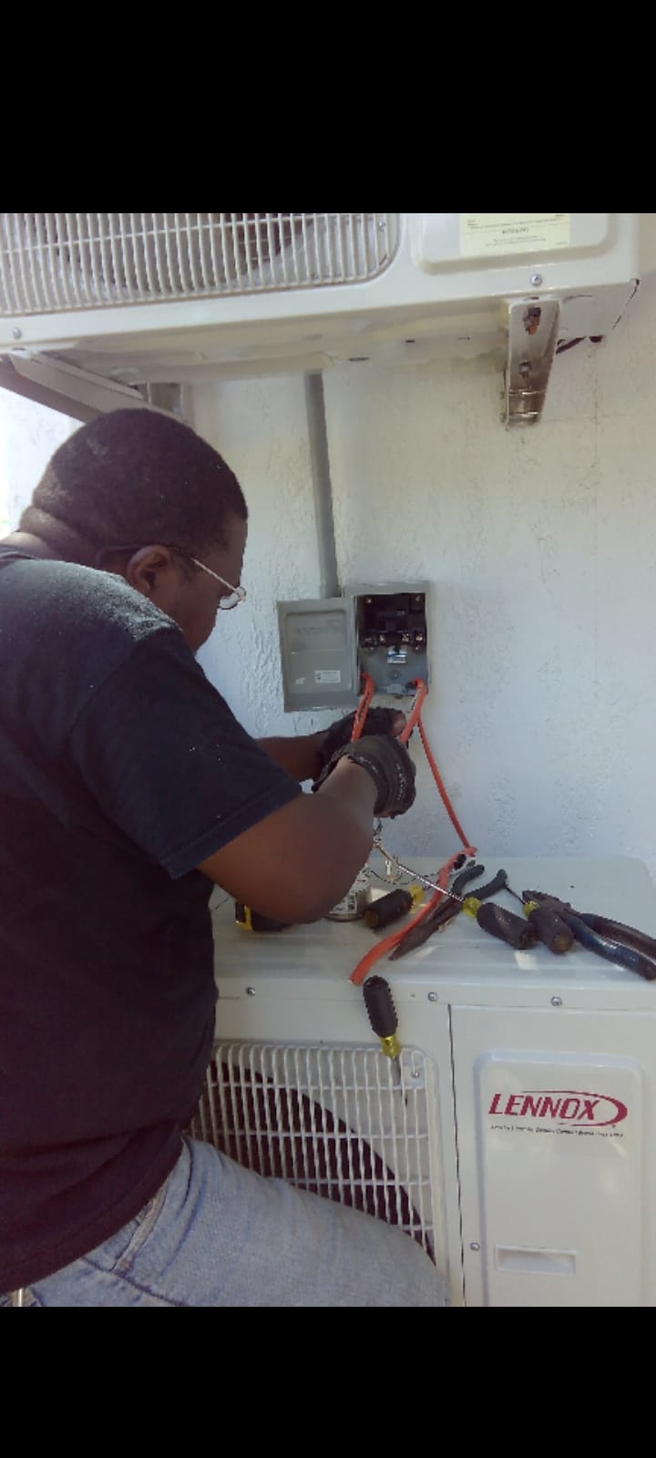 Technician wiring a Lennox outdoor AC condenser at the disconnect