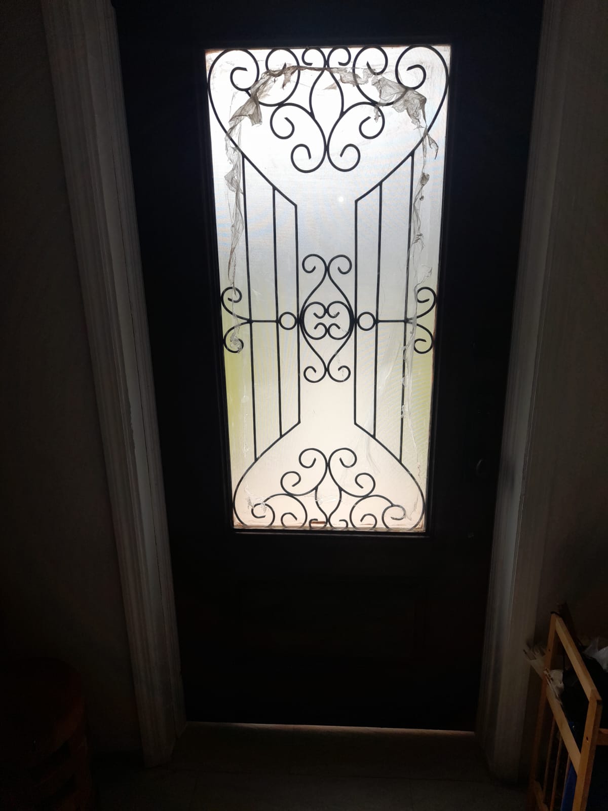 The finished door from inside, black-painted face with a decorative wrought-iron grill over the glass