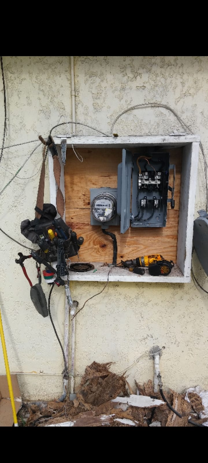 Outdoor electrical service replacement in progress, meter and disconnect mounted on fresh plywood backing