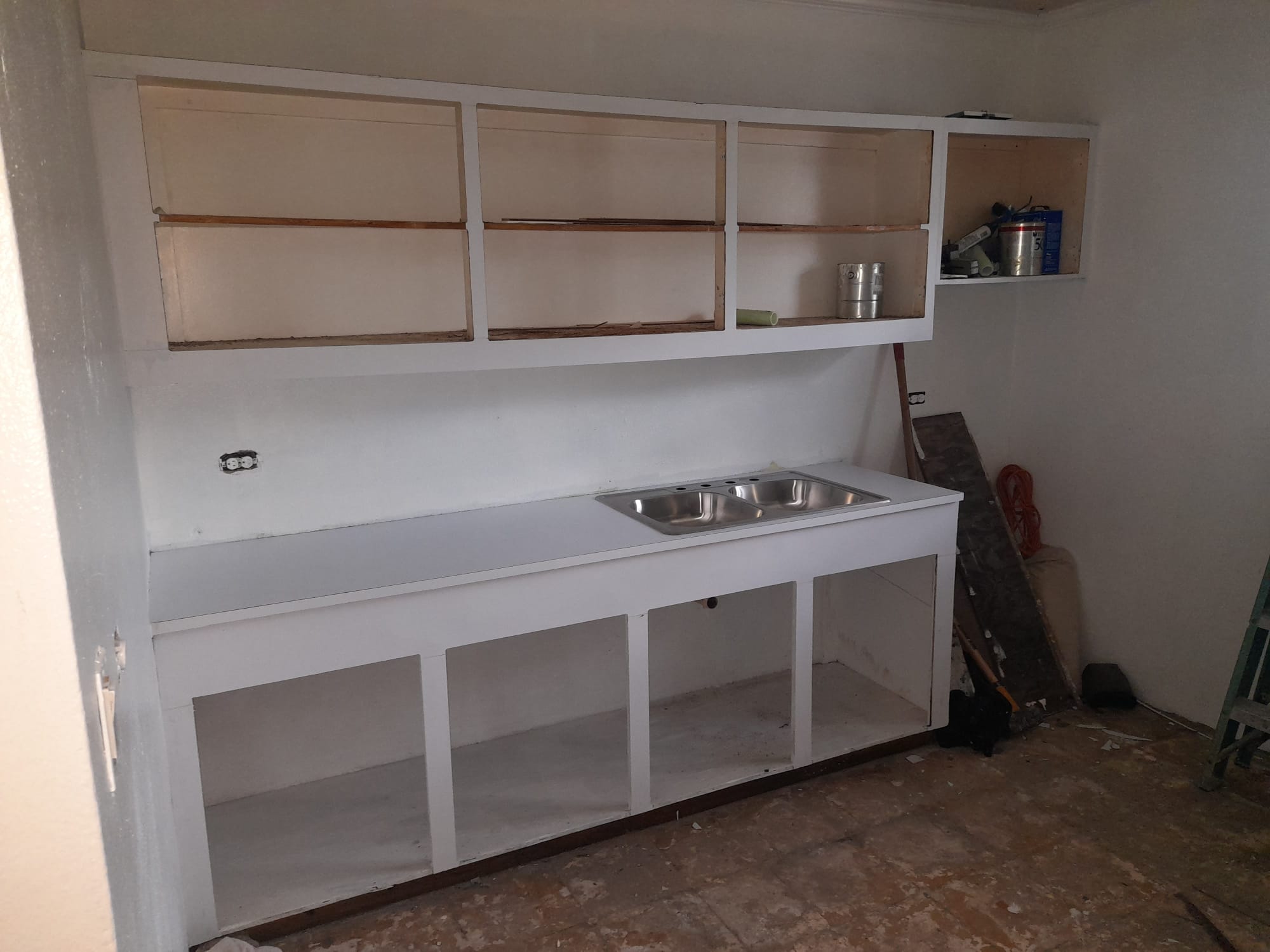 Primed white cabinet door panels leaning against mounted kitchen cabinet boxes