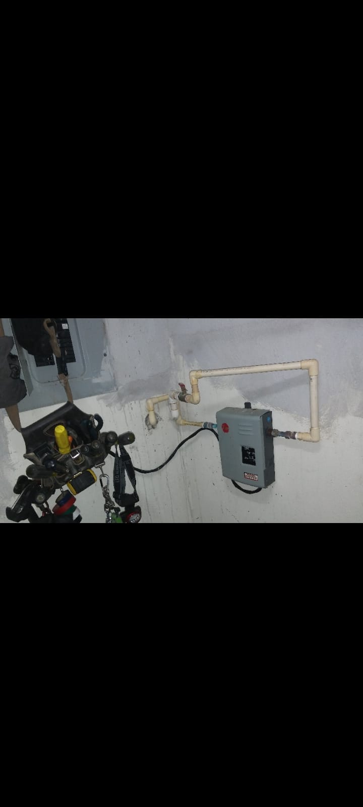 Small Rheem unit installed on a wall with a PVC pipe loop and shutoff valves
