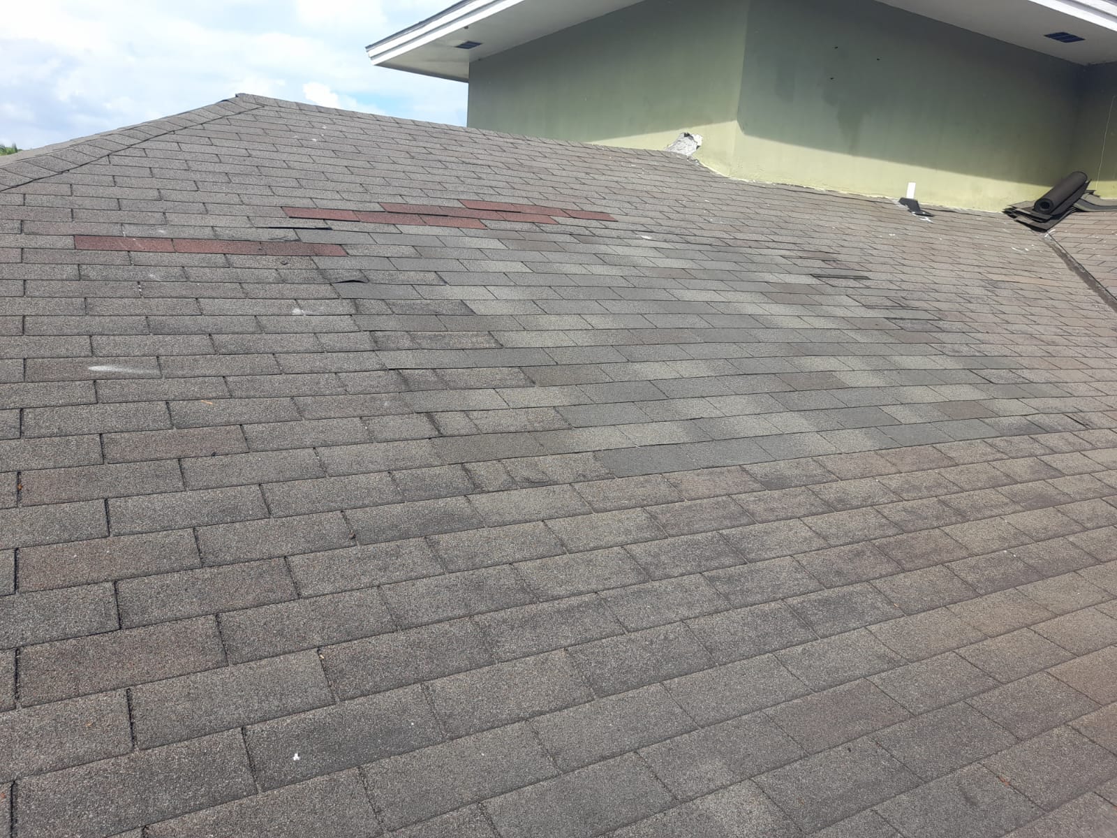 Same roof after repair, fresh shingles laid clean to the wall
