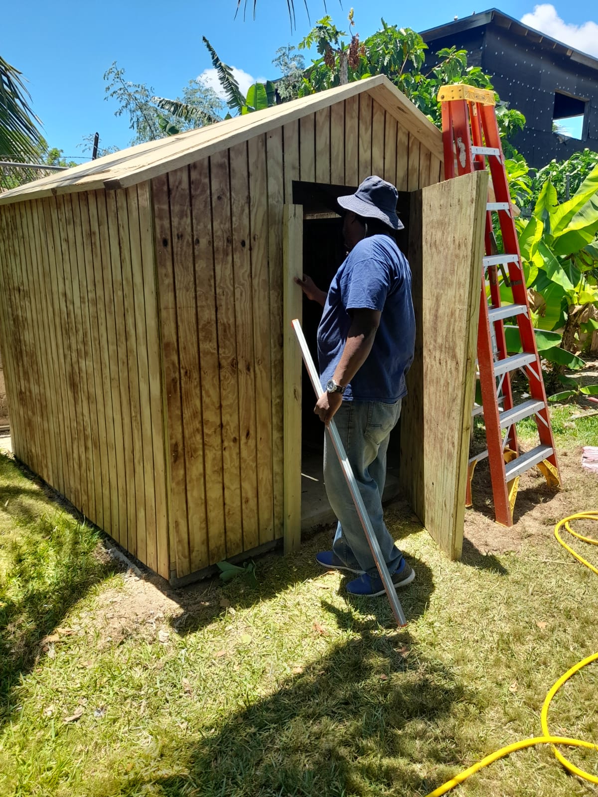 Worker installing the door on the natural-wood shed mid-build